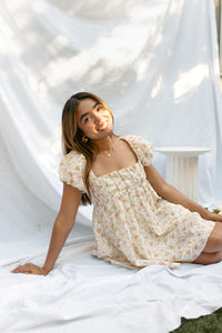 mini cream babydoll dress floral pattern  puff sleeves adjustable flowy pleated criss cross back bow