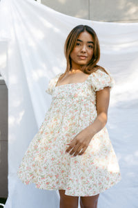mini cream babydoll dress floral pattern  puff sleeves adjustable flowy pleated criss cross back bow