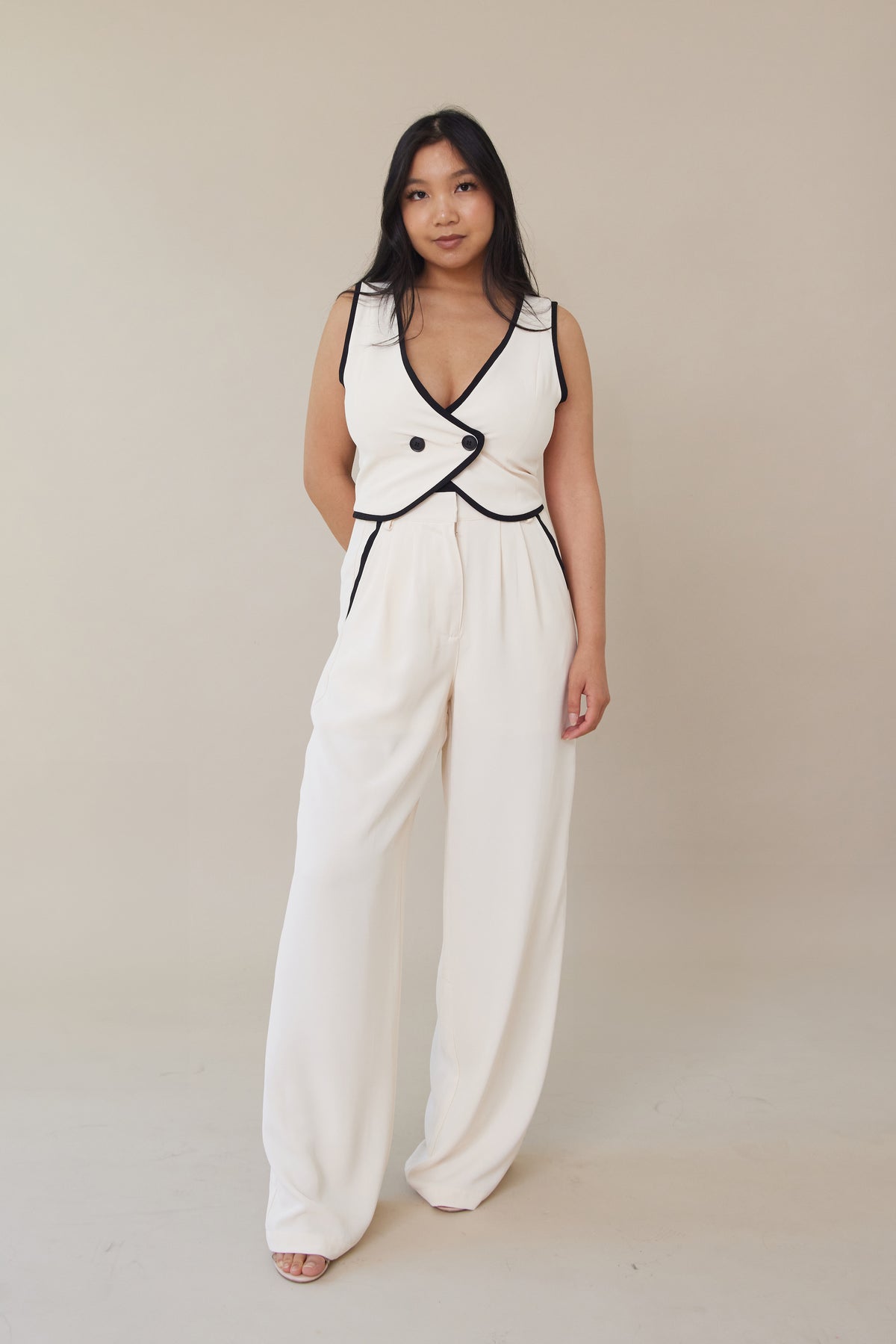 cream high waisted trouser pants relaxed fit black lining accents slight pleating button zipper closure flowy straight leg fit bottoms