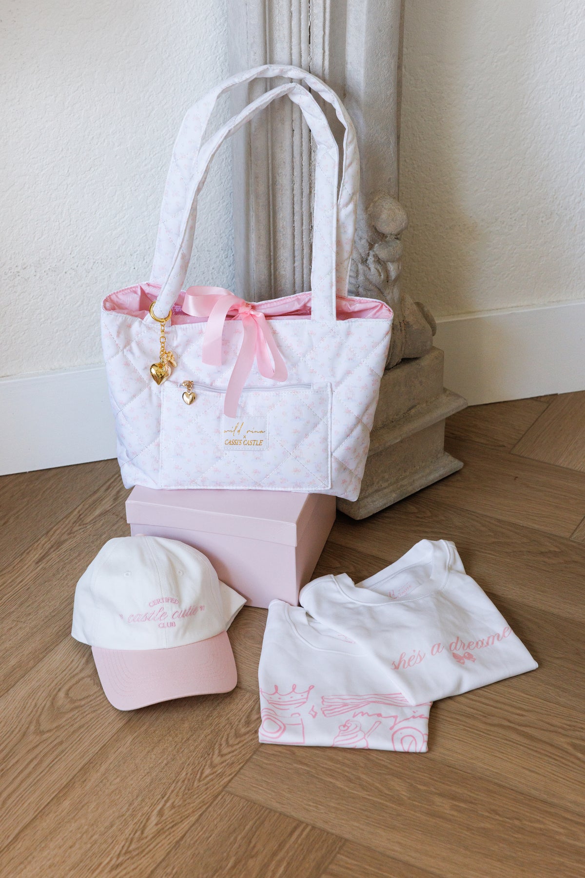 pink girly style bundle box that includes she's a dreamer baby tee snacks baby tee baseball hat quilted tote bag gold heart bag charm fashionable accessory bundle