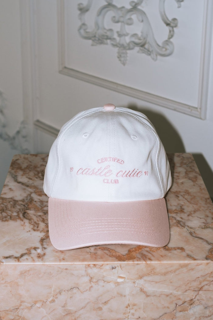 cream colored baseball hat with pink hill embroidered certified castle cutie script pink 1997 embroidered bow on back adjustable ties girly style cap