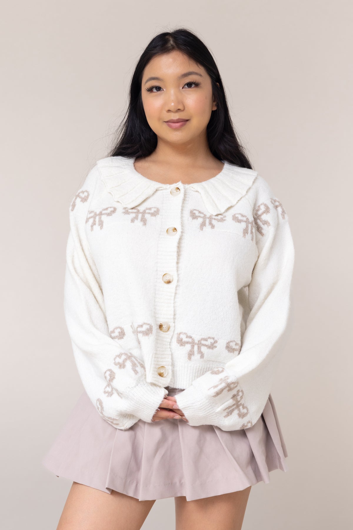 cream cardigan long sleeve button front closure cuffs frill collared round neckline grey bow pattern design