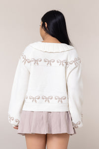 cream cardigan long sleeve button front closure cuffs frill collared round neckline grey bow pattern design