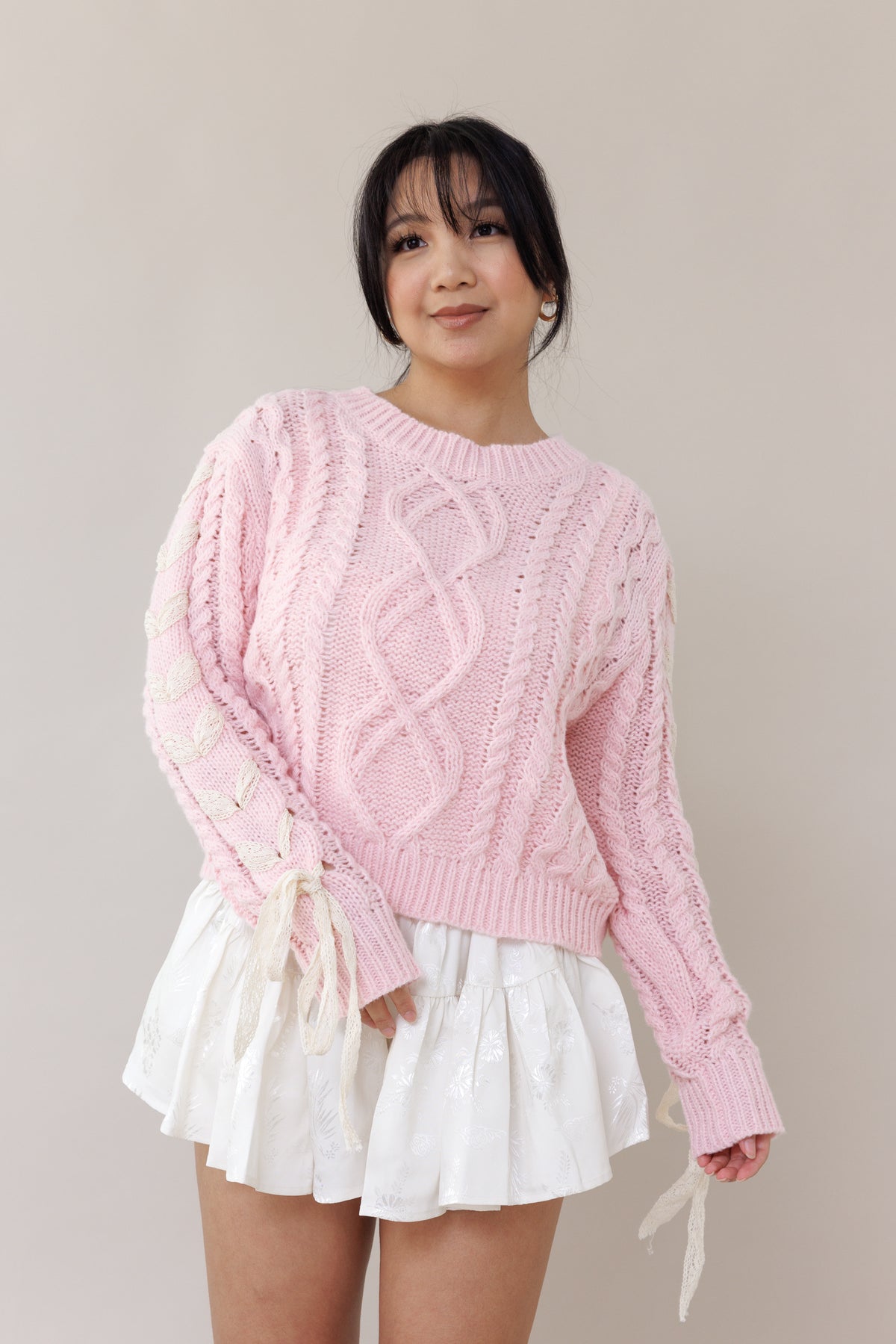 pink cable knit pullover long sleeve sweater round neckline ribbed cuffs lace trim bow romantic fashion cozy wear casual outfit fall winter spring style